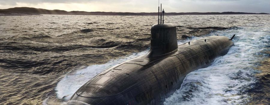 A nuclear-powered attack submarine on the surface in heavy sea.