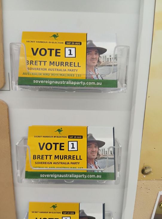 Vote 1 Brett Murrell cards in acrylic holders on a community noticeboard.