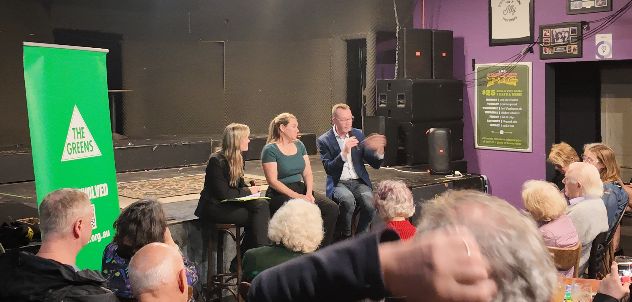 The panel seated on stage taking a question from the audience.