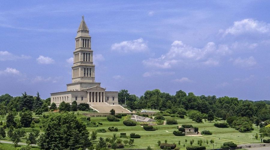 The George Washington Masonic National Memorial on a green hill: a stone temple base with a Doric portico, from which rises a tiered setback tower topped by a stepped pyramidal spire.